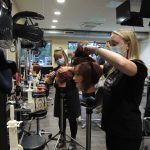 Hairdressing students practicing on models in a hair salon.