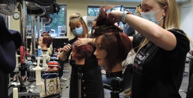 Hairdressing students practicing on models in a hair salon.