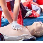 A person performing CPR on a first aid dummy