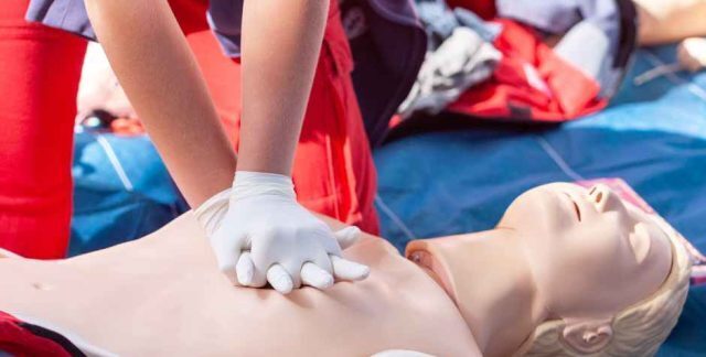 A person performing CPR on a first aid dummy
