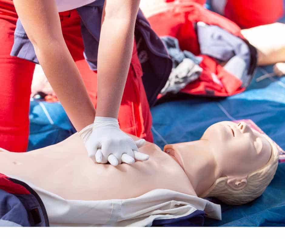 A person performing CPR on a first aid dummy