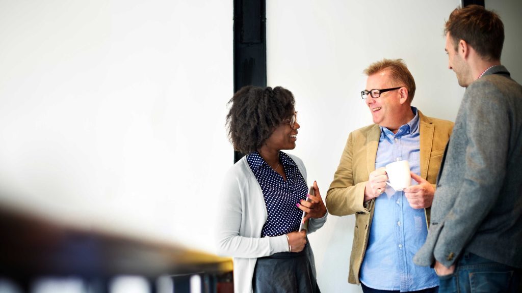 Three people in office attire having a discussion.