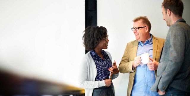 Three people in office attire having a discussion.