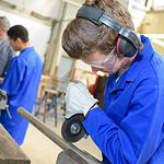 student in overalls and protective gear working in a workshop