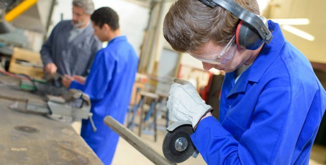 student in overalls and protective gear working in a workshop