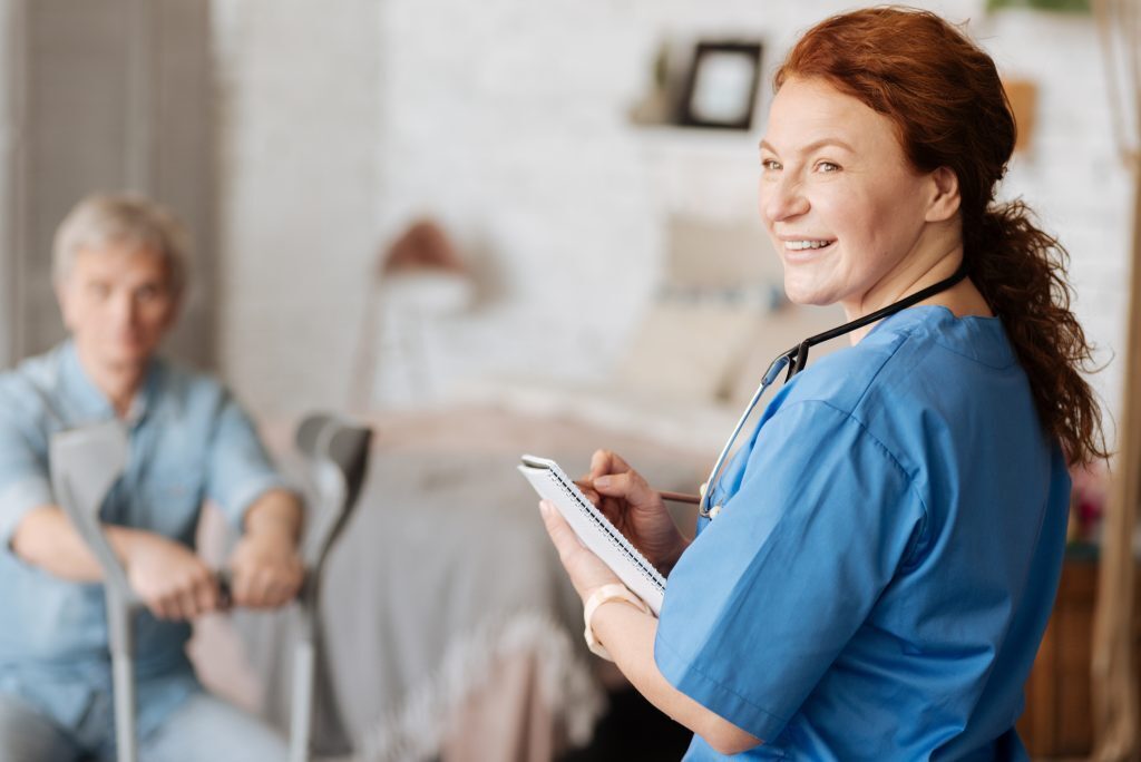 A nurse taking care of an elderly gentleman with crutches