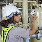 A female engineer in hard hat and high vis inspecting a boiler