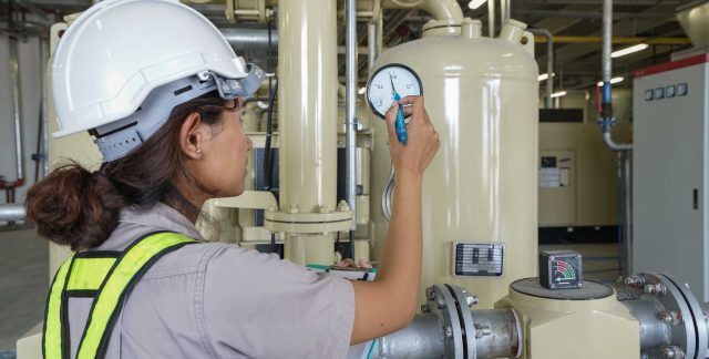 A female engineer in hard hat and high vis inspecting a boiler