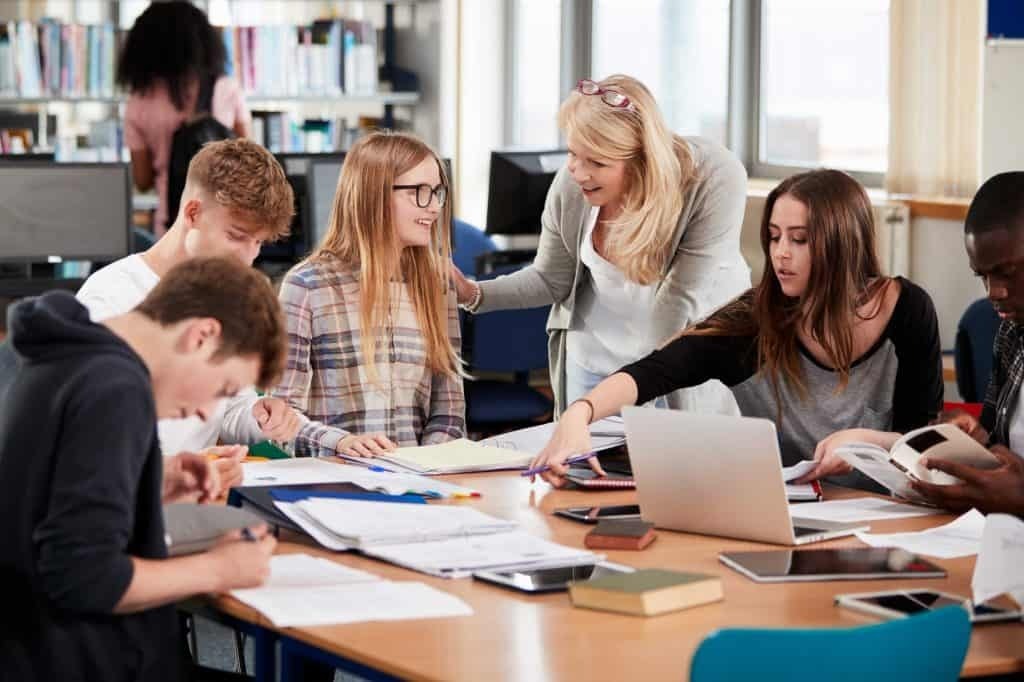 A group of students studying around a table with a teacher