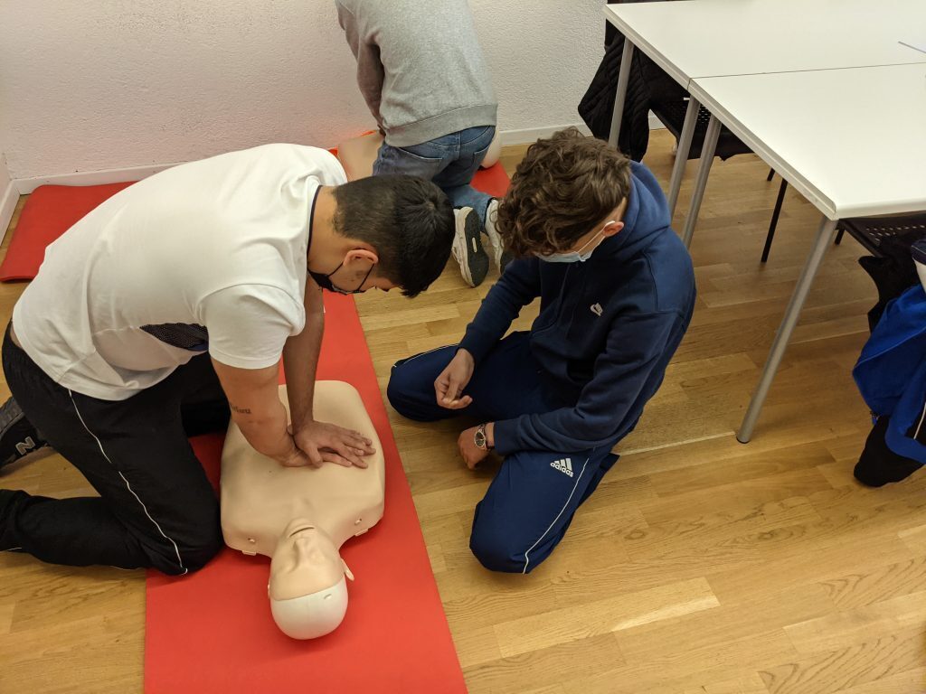 Students practicing CPR on a dummy in a classroom