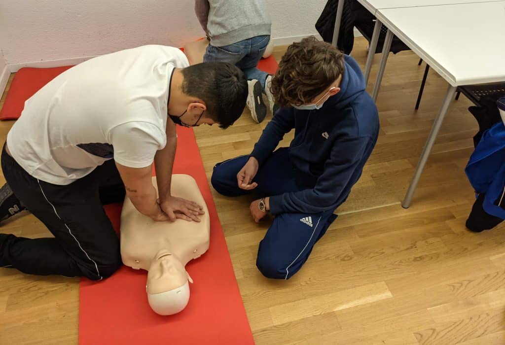 Students practicing CPR on a dummy in a classroom