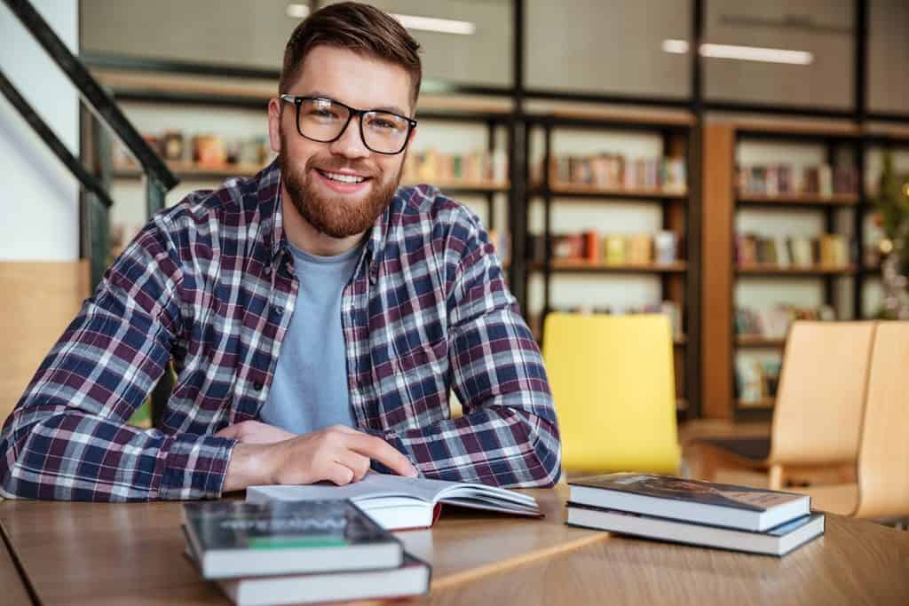 A student studying in a library with a pile of books