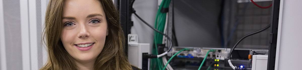 A female computing student by a server rack