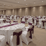 Event space set up with round tables and chairs. Table and chairs have linens and seat covers.